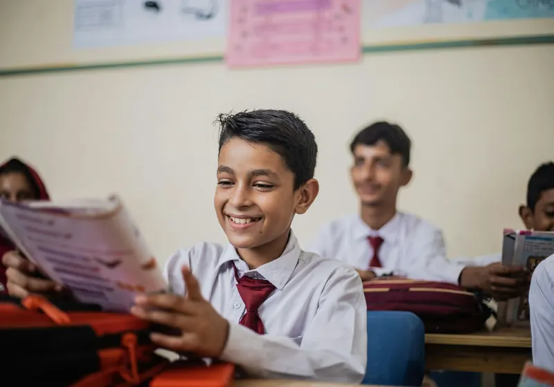 A smiling schoolboy reading in a classroom