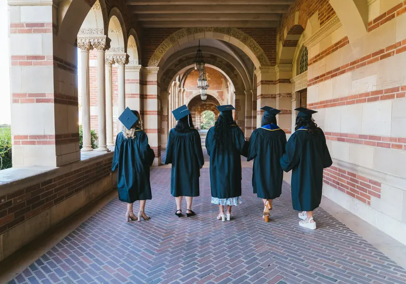 Graduates in gowns walking through a university arcade
